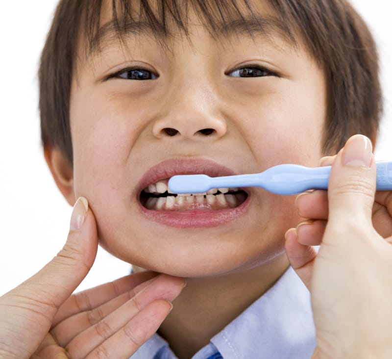 Kid getting help brushing teeth